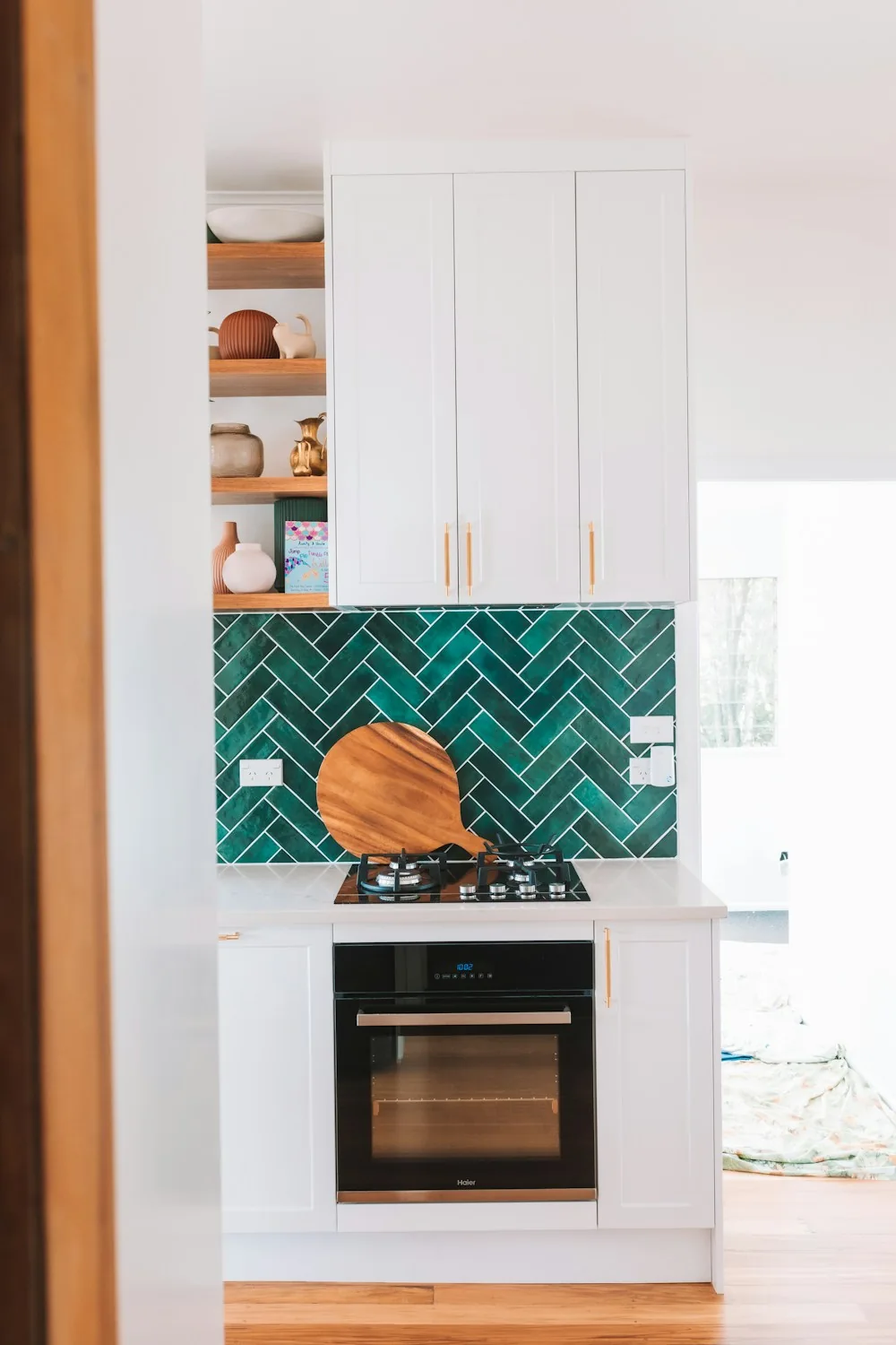 Green herringbone tile backsplash above a kitchen counter